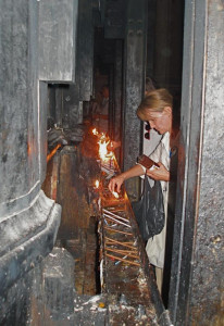 Lighting candles on girder that braced the Tomb of Christ before restoration in 2017 (Seetheholyland.net)